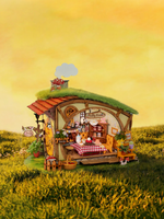 Front view of Rolife Fluffy Grove DG184 miniature house with a lit cottage interior in a sunset meadow