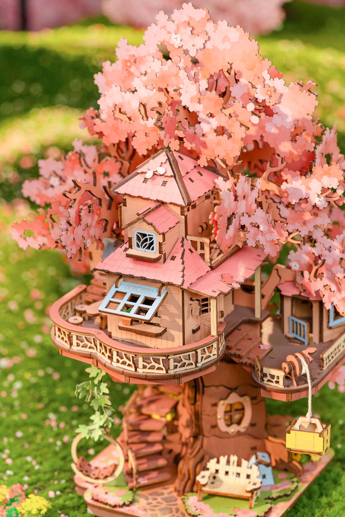 Close-up of Rolife Sakura Tree House TGS04 showing pink blossoms, balcony, stairs and small treehouse windows