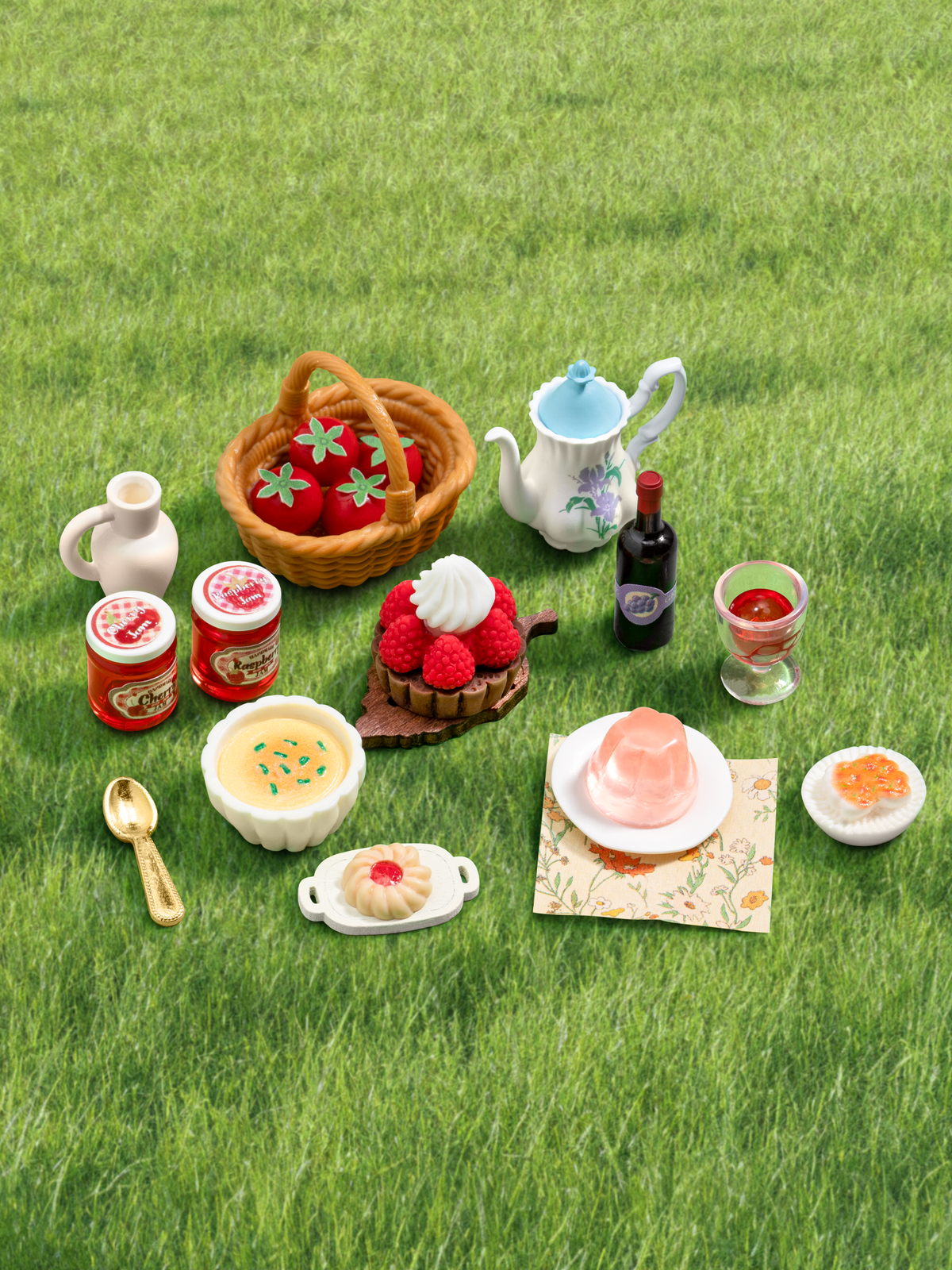 Rolife Fluffy Grove DG184 miniature accessories arranged on grass, including teapot, cakes, jam jars and basket